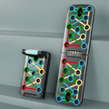 A foldable push-up board shown in two positions on a light gray surface, with colorful printed exercise path graphics across the metal surface. 